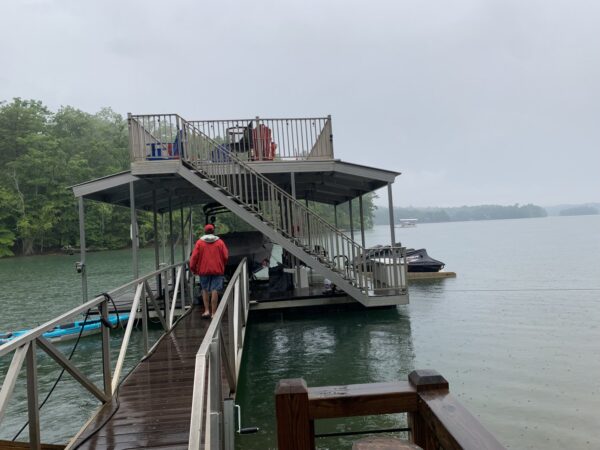 A waterfront structure featuring a gable roof, sundeck, and boat lift