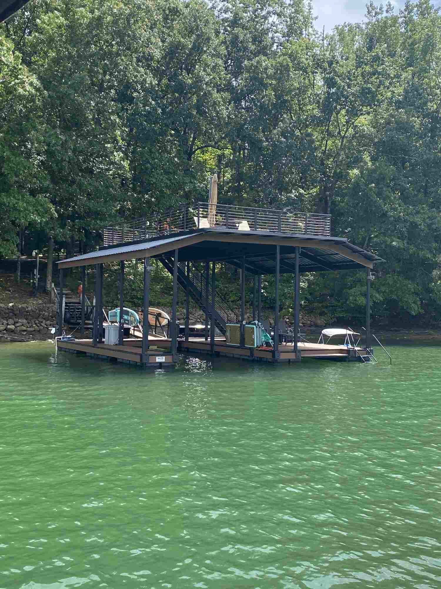 A dock with space for a single boat, featuring a rooftop adorned with comfortable sitting chairs