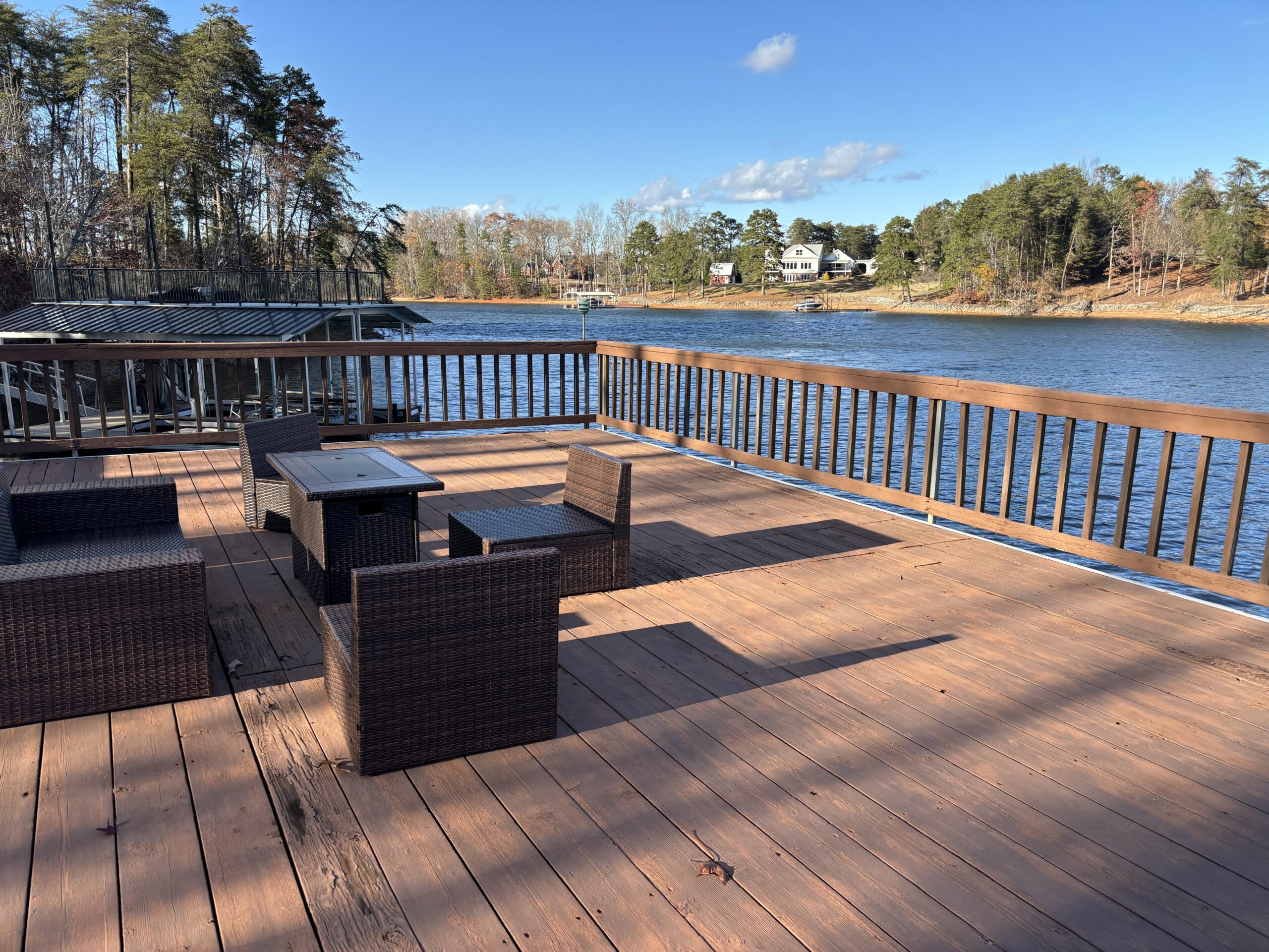 A sundeck with patio furniture overlooking a lake.